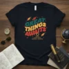 Great Things Awaits text in retro font with comets and pyramid graphic on a black t-shirt