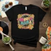 Groovy Mama text in retro font surrounded by colorful flowers, butterflies, and a rainbow on a black t-shirt