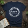 Navy t-shirt with white text "GROW EMBRACE THE JOURNEY" inside a floral wreath graphic
