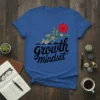 Growth Mindset T-Shirt with black cursive text and a graphic of plants growing in stages towards a red flower