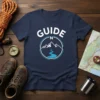 Navy t-shirt with white "GUIDE N" text above a circular graphic of mountains and a river, symbolizing adventure and navigation