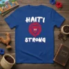 Blue t-shirt with bold white text "HAITI STRONG" and a red lion graphic featuring the Haitian flag in its face