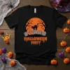 Black t-shirt with "Halloween Party" text, spooky black cat, and graveyard graphic under an orange moon