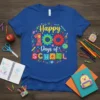 Happy 100 Days of School text with colorful gears, pencils, scissors, and globes graphic on a blue t-shirt