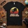 Happy Cat Adventures text with a black cat silhouette against a retro sunset graphic on a t-shirt