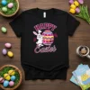 Happy Easter text with a cartoon bunny painting a colorful Easter egg, on a black t-shirt