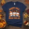 Happy Fall Brush Them All t-shirt with cartoon teeth wearing fall hats and scarves, surrounded by autumn leaves and pumpkins