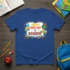 Happy First Day of School text with owl, books, school bus, and chalkboard graphic on a blue t-shirt