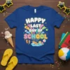 Happy Last Day of School text with colorful graphics, including books, graduation caps, and beach elements, on a blue t-shirt