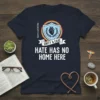 Navy t-shirt with white text "Hate Has No Home Here" and "Unity & Care" banner, featuring a shield with a