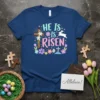He Is Is Risen Easter Christian T-Shirt with cross, flowers, and bunny graphic