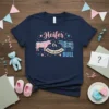 Navy blue t-shirt with "Heifer Or BULL What Will Baby Be?" gender reveal design, featuring pink floral heifer and blue