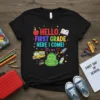 Black t-shirt with "HELLO FIRST GRADE HERE I COME! It's me ❤️" text and school graphics like a bus, backpack
