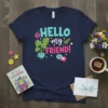 Navy blue t-shirt with "HELLO my FRIEND!" in colorful, playful typography, featuring a cute potted plant and speech bubbles