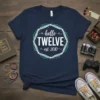 Navy blue t-shirt with "hello TWELVE est. 2010" text in white and teal circular graphic, celebrating a 12th birthday