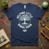 Helping Little Minds Grow text with a tree and book graphic on a navy t-shirt, perfect for teachers and educators