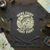 Here Fishy Fishy Fishy Fishy bass fishing quote on a dark t-shirt with a graphic of a jumping fish