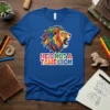 HE'S NOT A TAME LION text with a colorful, roaring lion head graphic on a blue t-shirt