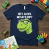 Hey Guys Whats Up? text above a cartoon green T-Rex wearing glasses on a navy blue t-shirt