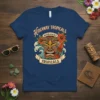 Hideaway Tropicals t-shirt design featuring a fierce tiki mask, hibiscus flowers, ocean waves, and a surfboard