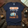 Home Is Where You Park It text with camper graphic, paw print, mountains, and campfire design on a navy t-shirt