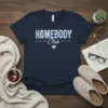 Homebody Club text with blue gingham heart on a navy t-shirt, ideal for introverts and home lovers