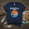 Navy blue t-shirt with "Honeymoon Vibes" text and a circular tropical sunset graphic featuring palm trees and a sailboat