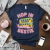 Navy blue t-shirt with "Hop In Struggle Bus Bestie" text and a yellow double-decker bus graphic, surrounded by pink clouds