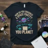 T-shirt with the text "How do you organize a space party? You planet" featuring a cartoon planet, UFOs, and musical