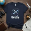 Hubble Space Telescope graphic t-shirt design featuring a satellite in orbit with stars and galaxies, text reads "Hubble SPACE TELESCOPE"