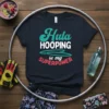T-shirt design with text "Hula HOOPING is my SUPERPOWER" in teal, white, and pink, surrounded by a hula hoop
