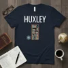 Navy blue t-shirt with "HUXLEY" in white text, a wooden bookshelf graphic, and a blue atom symbol