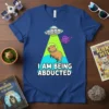 Capybara in astronaut helmet being abducted by a UFO with text "I AM BEING ABDUCTED" on a blue t-shirt
