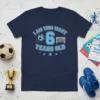 Navy blue t-shirt with light blue text and graphics that reads "I Am This Many 6 Years Old" with a