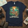 I Believe In Bigfoot Vacations text with Bigfoot playing guitar in a hammock design on a navy t-shirt