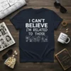 Navy t-shirt with white text "I CAN'T BELIEVE I'M RELATED TO THOSE PEOPLE" above cartoon figures