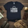 Navy t-shirt with white text "I CHOOSE FREEDOM THAT'S HOW I LIVE" and mountain graphic, designed for adventure lovers