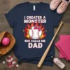 I CREATED A MONSTER SHE CALLS ME DAD text with a baseball graphic and flames on a navy t-shirt