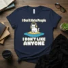 I Don't Hate People I DON'T LIKE ANYONE text with a grumpy cat wearing headphones on a small island graphic