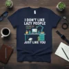 Navy t-shirt with white text "I DON'T LIKE LAZY PEOPLE JUST LIKE YOU" and a desk setup graphic with laptop