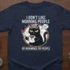 Grumpy black cat with knife and coffee mug on a t-shirt, reading "I Don't Like Morning People Or Mornings Or