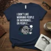Navy t-shirt with white text "I DON'T LIKE MORNING PEOPLE OR MORNINGS... OR PEOPLE..." and a cartoon coffee pot wearing