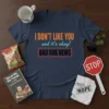 I DON'T LIKE YOU and it's okay! BAD Y#& NEWS quote on a navy blue t-shirt, featuring bold orange and