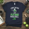T-shirt with "I DON'T RETIRE I JUST PLAY MORE PICKLEBALL" text, featuring a cartoon man playing pickleball and pickleballs
