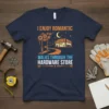 Navy blue t-shirt with orange and blue text reading "I Enjoy Romantic Walks Through The Hardware Store," featuring a graphic