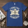 Skeleton holding a bone and text that reads "I Fond Ths Humerus" on a blue t-shirt, Halloween pun design