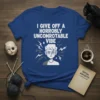 Blue t-shirt with white text "I GIVE OFF A HORROBLY UNCOMROTATABLE VIBE" and a graphic of an annoyed person with