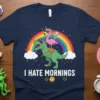 I Hate Mornings t-shirt with a T-Rex riding a flamingo unicorn under a rainbow, funny quote design