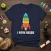 Navy t-shirt featuring a rocket design illustrating Maslow's Hierarchy of Needs with text "I HAVE NEEDS" below