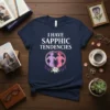 T-shirt with white text "I HAVE SAPPHIC TENDENCIES" above a graphic of two figures within a peace sign, surrounded by